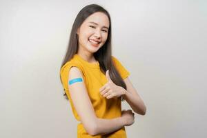 Portrait of pretty, beautiful asian young, teenage attractive after getting, receive anti virus vaccine covid-19. Showing arm on white bandage isolated on white background, copy space. photo