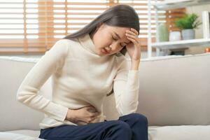 Flatulence asian young woman, girl hand in stomach ache, suffer from food poisoning, abdominal pain and colon problem, gastritis or diarrhoea. Patient belly, abdomen or inflammation, concept. photo