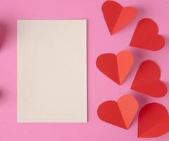 Red Heart paper and blank with note card on wall background photo