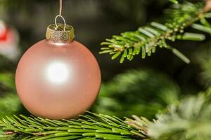 rosado pelota colgando en un navidad árbol detalle foto