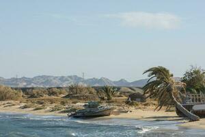 landscape with beach and old abandoned boats and hight mountains photo