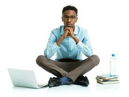 african american college student with laptop, books and bottle of water sitting on white photo