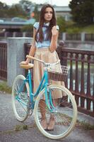 joven mujer hermosa, elegantemente vestida con bicicleta foto