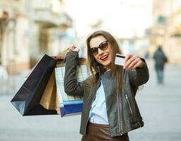 hermosa mujer con compras pantalones y crédito tarjeta en el manos en un calle foto