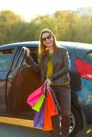 Smiling Caucasian woman putting her shopping bags into the car photo