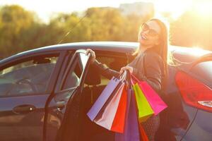 Smiling Caucasian woman putting her shopping bags into the car photo