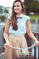 joven mujer hermosa, elegantemente vestida con bicicleta foto