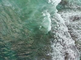 blue and green waves crashing against the reef making a beautiful natural pattern. photo