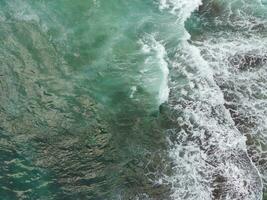 blue and green waves crashing against the reef making a beautiful natural pattern. photo