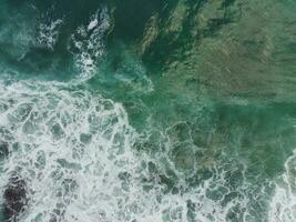 blue and green waves crashing against the reef making a beautiful natural pattern. photo