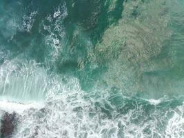 blue and green waves crashing against the reef making a beautiful natural pattern. photo