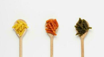 Uncooked pasta torti on wooden spoons on white background. photo