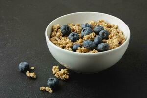 Granola with blueberry in white bowl. photo