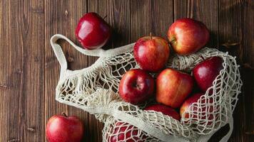 Red apples in a grid bag on a wooden background photo