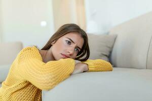 Upset woman frustrated by problem with work or relationships, sitting on couch, covered face in hand, feeling despair and anxiety, loneliness, having psychological trouble photo