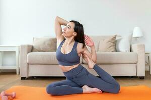 joven atractivo sonriente mujer practicando yoga, sentado en sirena pose, trabajando afuera, vistiendo ropa de deporte, meditación sesión, interior lleno longitud, hogar interior foto