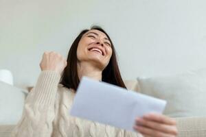 Cheerful Asian woman receiving invitation or good news about approved loan, mortgage, tax, insurance, getting notice about acceptance of statement photo