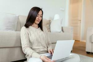 Portrait of casual asian woman relax sit on the floor use computer laptop. Thinking asian Freelance small business owner sme virtual, work from home concept. photo