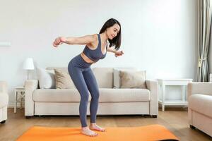 asiático mujer ejercicio con pesas a hogar. contento hembra haciendo brazo rutina de ejercicio utilizando pesas foto