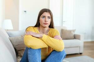 anxious worried woman sitting on couch at home. Frustrated confused female feels unhappy, problems in personal life, quarrel break up with boyfriend and unexpected pregnancy concept photo