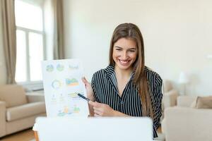 Focused business woman presenting charts and graphs on video call online. Young business woman having conference call with client on laptop. Young woman explaining how business work photo