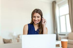 Happy young woman in headphones speaking looking at laptop making notes, business woman talking by video conference call, Conference by webcam, online training, e-coaching concept photo