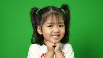 porträtt av Lycklig och rolig asiatisk barn flicka på grön skärm bakgrund, en barn ser på kamera. förskola unge drömma fylla med energi känsla friska och Bra begrepp video