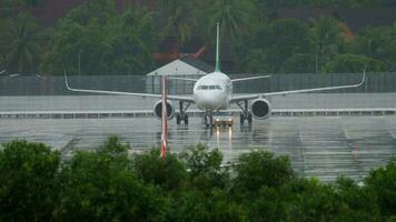 PHUKET, THAILAND NOVEMBER 28, 2019 - AirAsia Airbus A320 taxiing before take off and Spring Airlines Airbus A320 pushing back at background, rainy weather, Phuket International airport. video