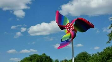Colorful pinwheel toy against the blue sky with white clouds. video