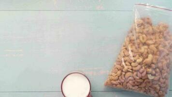 Cashew nut and glass of milk on table , flat lay video