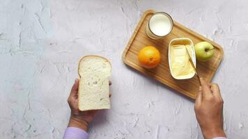 persoon hand- verspreiden boter op geroosterd brood met mes Aan houten bord video