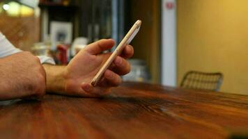 el teléfono es en el mano de un hombre sentado en un restaurante, un adolescente con un anillo en su dedo es utilizando su teléfono inteligente video