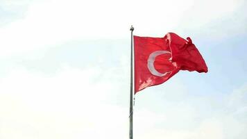 Image of a red Turkish flag attached to a pole waving in the wind, view of a red flag in the clear and beautiful sky video