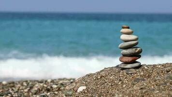 le image de empilés Zen des pierres sur le plage est une traditionnel croyance, une minuscule pierre la tour permanent sur le plage par le mer video
