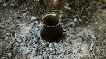 beeld van Turks koffie gekookt Aan steenkool brandend Aan de grond, visie van koffie gemaakt in een authentiek koffie pot video