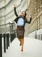 Delighted business woman jumping for joy while talking on the smart phone photo