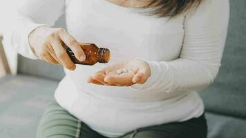 del hombre manos sostiene un azul cápsula y vaso de agua terminado el mesa, Listo a tomar medicamentos. enfermo hombre necesitar medicina desde dolor de cabeza y frío, analgésico, nutricional suplemento. salud cuidado concepto. video