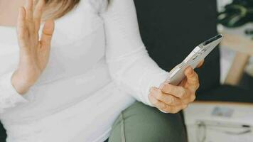 From above of positive adult female in casual outfit with headphones and tablet sitting on sofa with pillows in light studio video