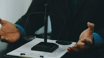 Business and lawyers discussing contract papers with brass scale on desk in office. Law, legal services, advice, justice and law concept picture with film grain effect video