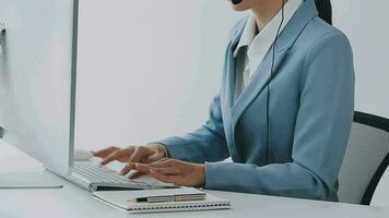 Call center agent with headset working on support hotline in modern office with copy space. Portrait of mature positive agent in conversation with customer over headset looking at camera. video