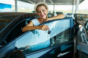 contento mujer en pie cerca un coche con llaves en mano - concepto de comprando un usado coche foto