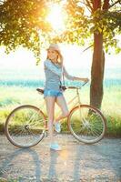 Lovely young woman in a hat riding a bicycle in a park photo