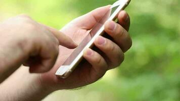 un teléfono retenida por un joven hombre en pie en el bosque, un hombre utilizando un teléfono con un dedo, natural vida, digital años video