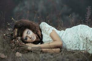 Young girl in the image of a bride lying on the ground photo