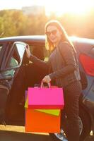 Smiling Caucasian woman putting her shopping bags into the car photo