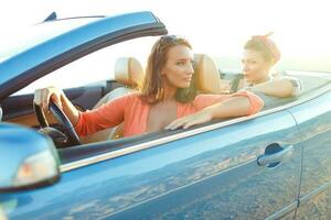 Two young happy girls driving a cabriolet photo