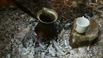 de beeld van de kop staand Aan de steen en de Turks koffie gekookt in de rood steenkool, de Mens liften de koffie pot met zijn hand- naar brouwen de koffie goed video