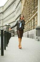 Businesswoman walking down the street while talking on smart phone photo