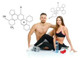 Athletic couple - man and woman after fitness exercise sitting with dumbbells with the chemical formula on background - concept of healthy life photo