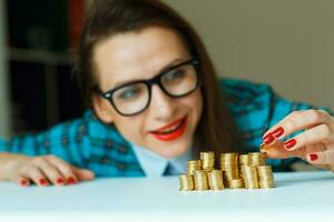 Smiling woman stacking gold coins into columns photo